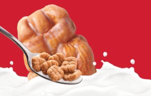 Tim Hortons Apple Fritter cereal on a spoon with milk beneath it on a red background.
