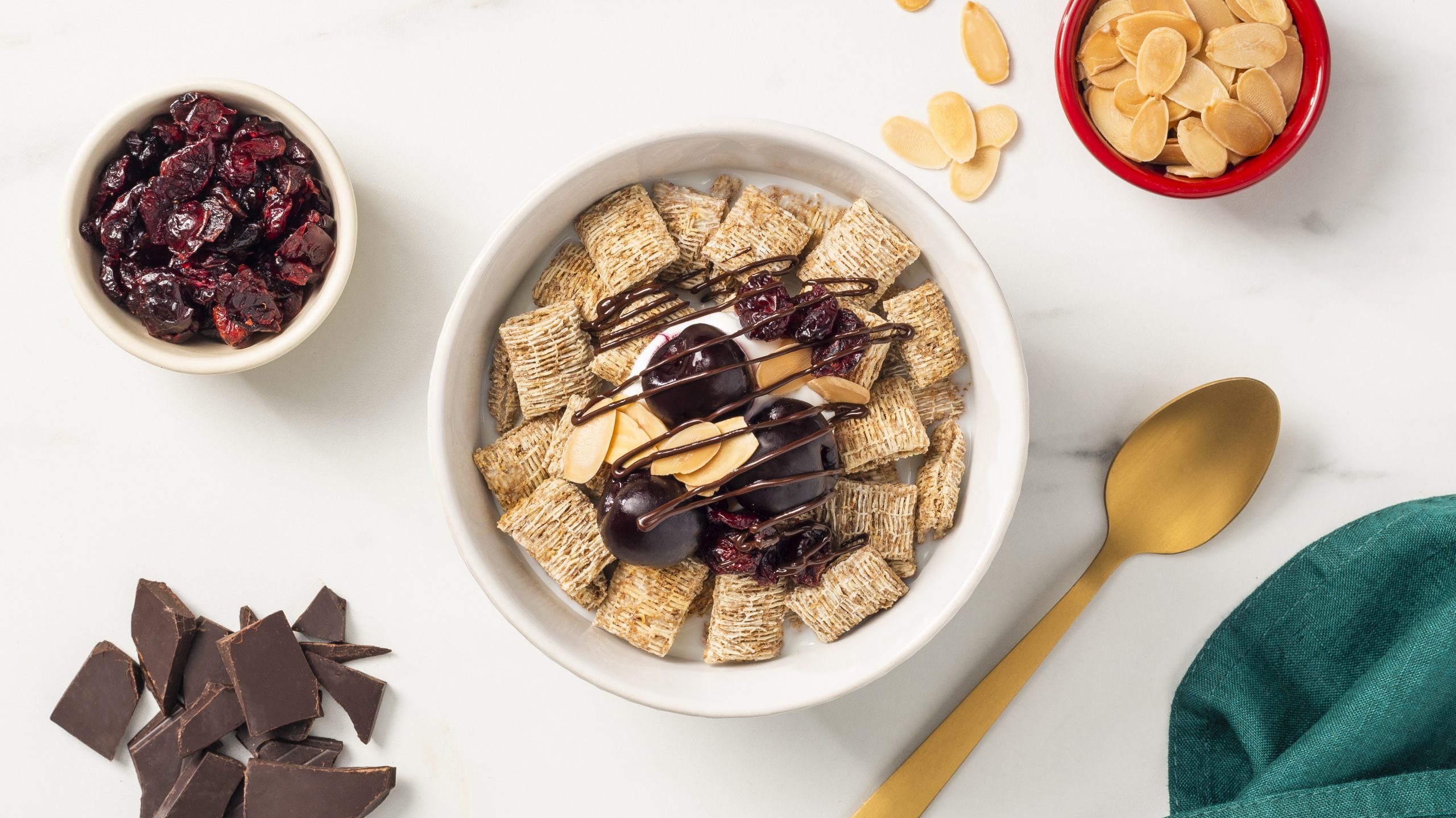 Spoon Sized Shredded Wheat in a bowl with cherries, yogurt and chocolate drizzle on top.