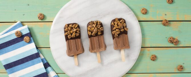 Chips Ahoy Cereal-Dipped fudgy ice pops on a white plate on a green background.