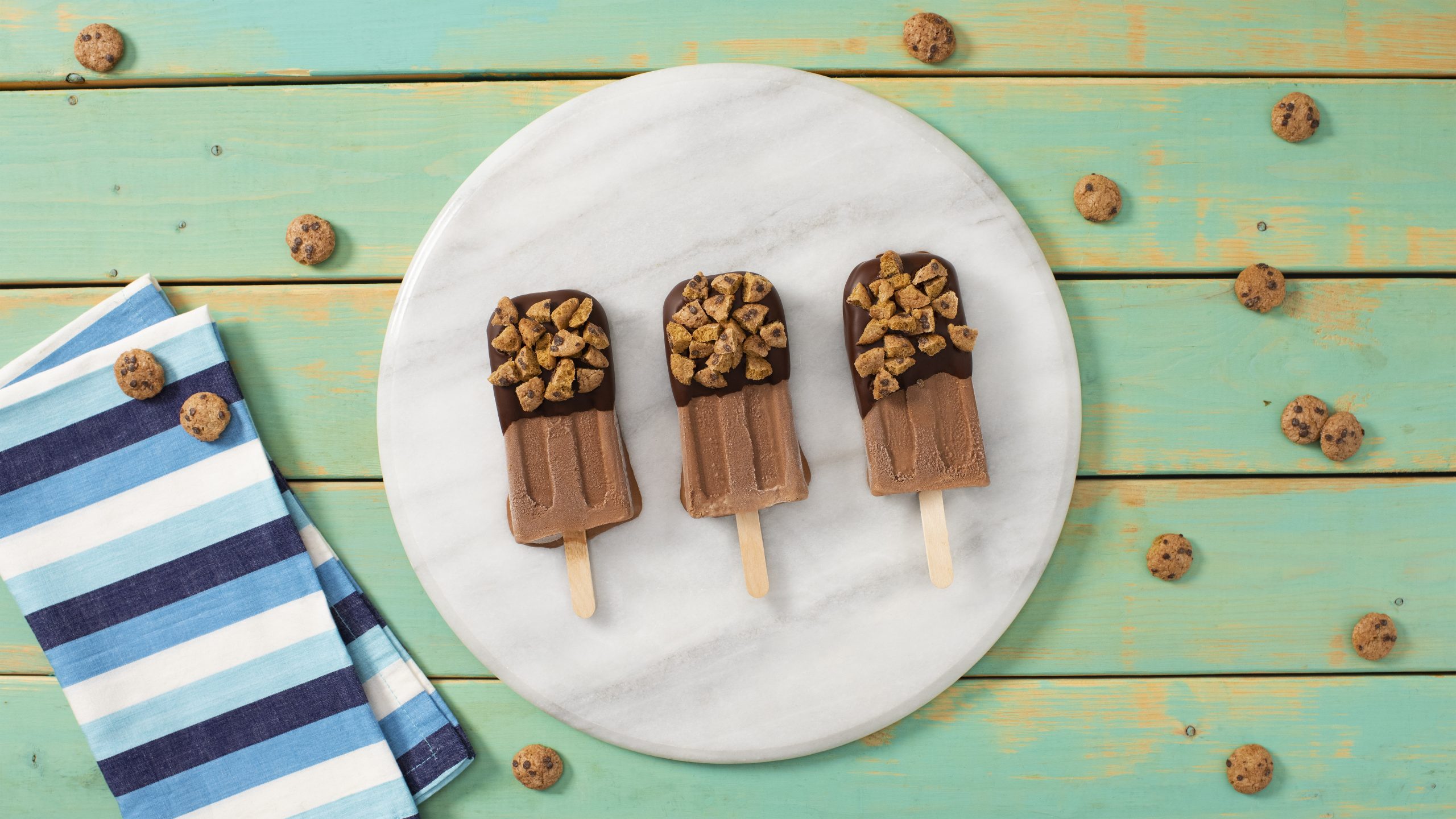 Chips-AHoy-Cereal-Dipped-Fudgesicle-Cheesecake-028-scaled Chips Ahoy Cereal-Dipped fudgy ice pops on a white plate on a green background.