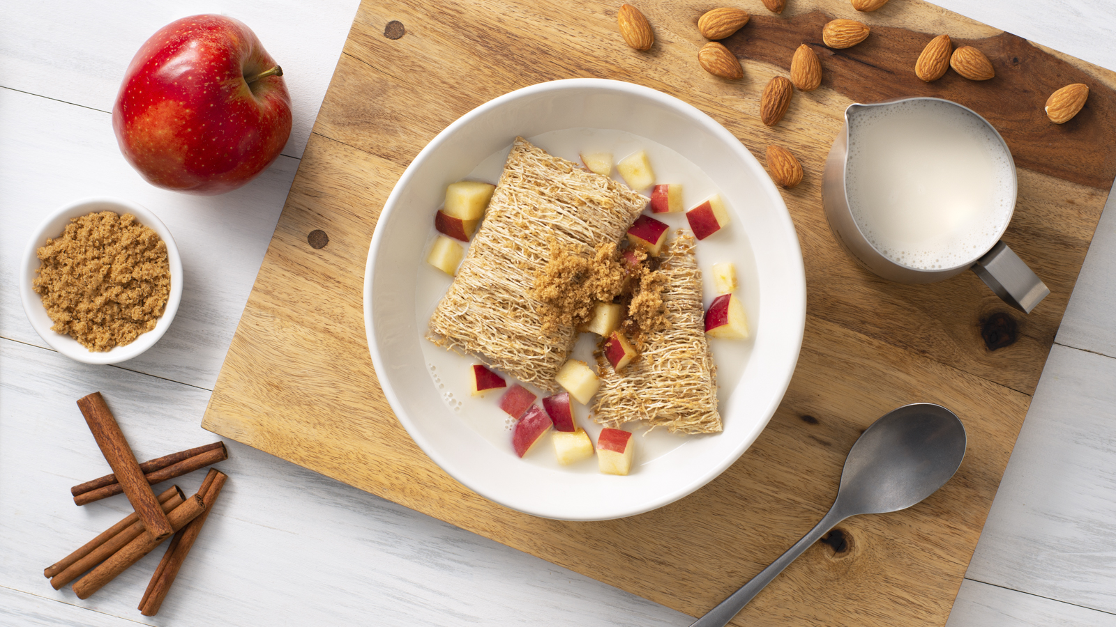 Shredded Wheat biscuits in a bowl of milk with cinnamon and apple on top.