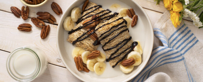 Shredded Wheat Go Bananas breakfast bowl with pecans and banana slices on top.