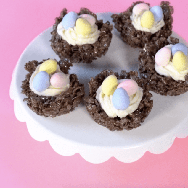 Cocoa Pebbles spring nests on a white plate on a pink background. 