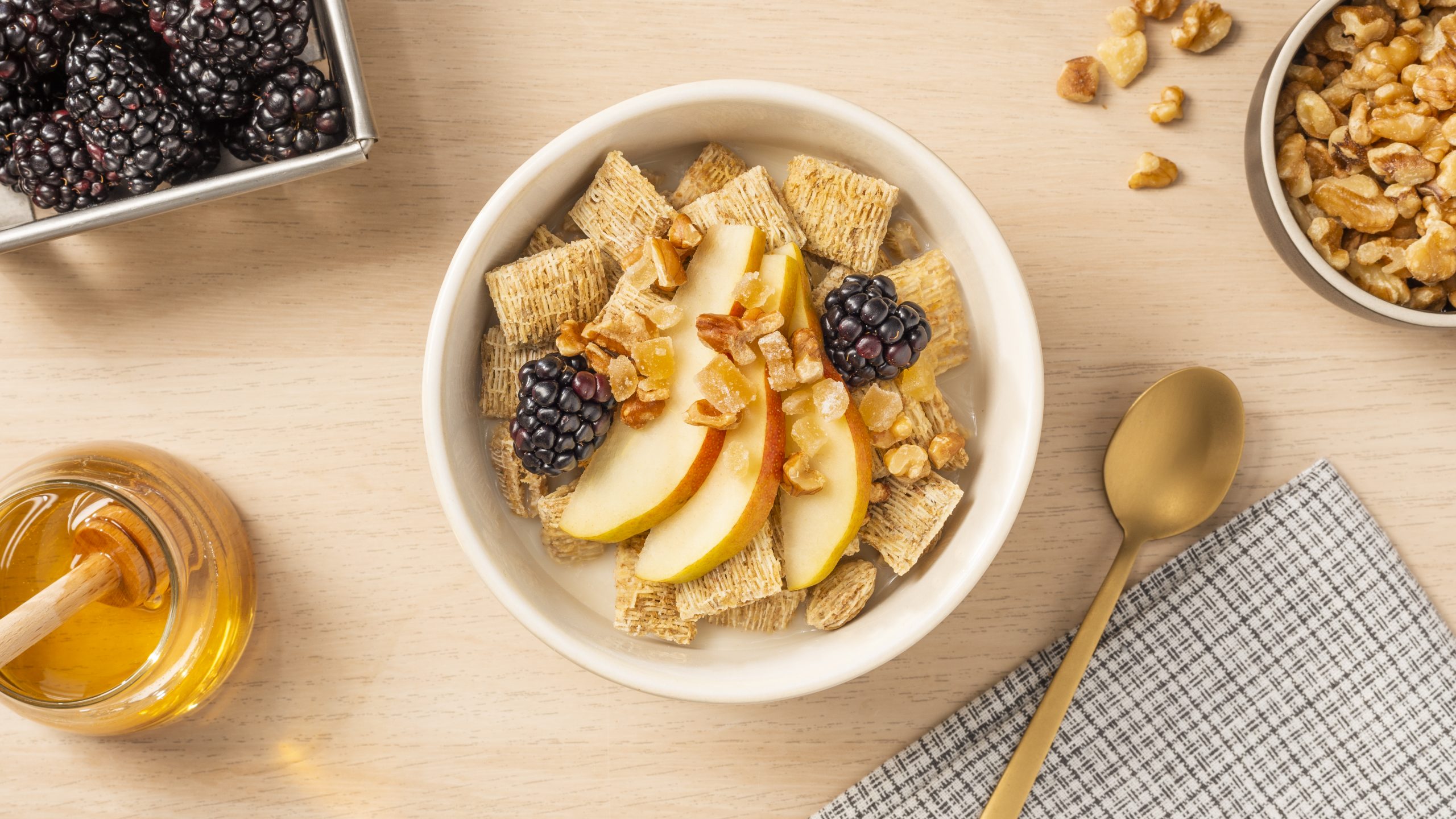 Pear Ginger Crisp in a white bowl with honey, blackberries and nuts on top.