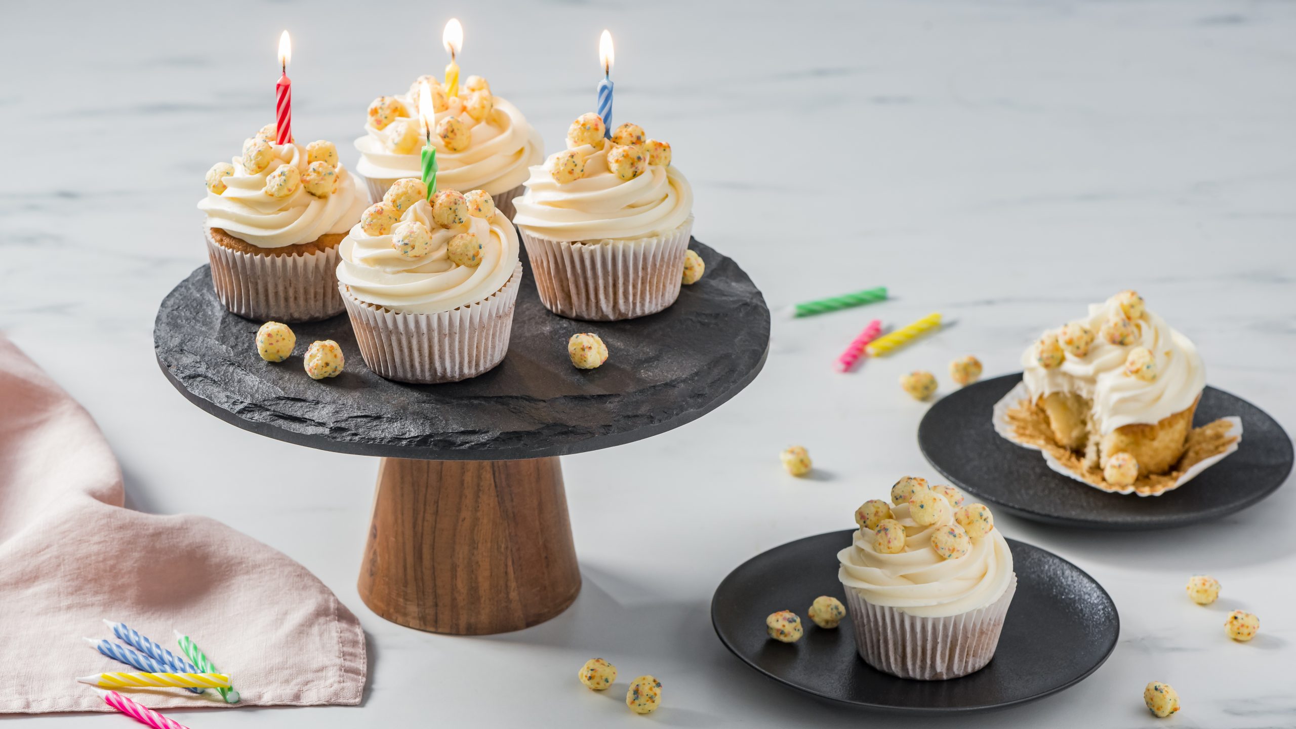 Timbits Birthday cake cereal cupcakes on a black platter and plates with candles.