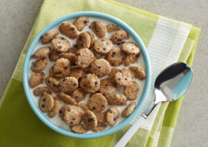 Blue bowl of cookie cereal on a green cloth.