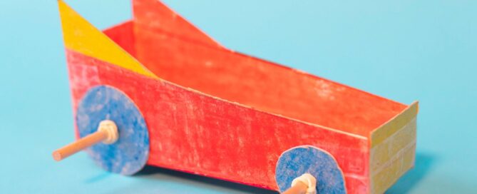 Red, yellow and blue paper car craft on a blue background.