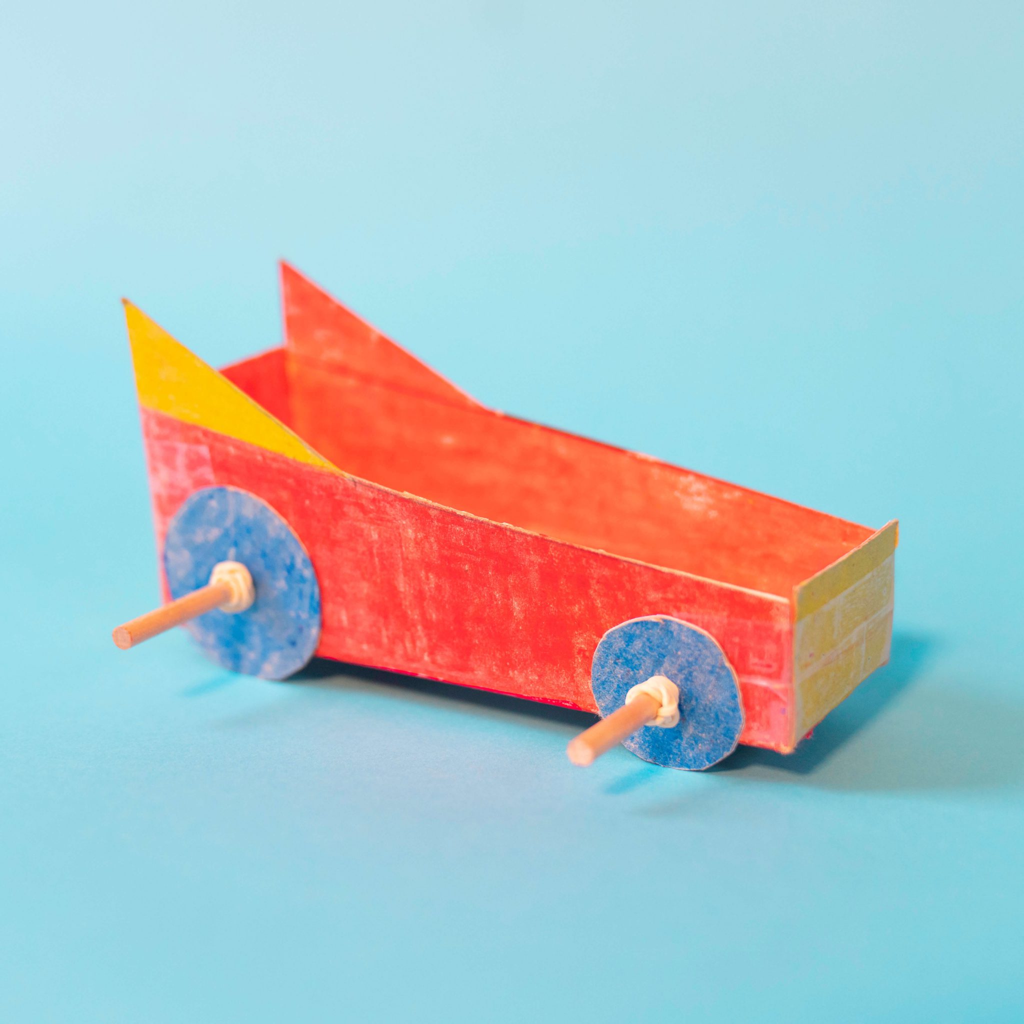 Red, yellow and blue paper car craft on a blue background.