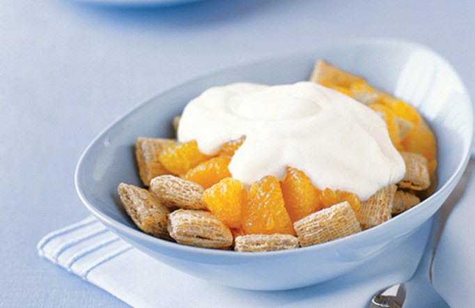 Post Shredded Wheat with Yogourt & Fruit in a blue bowl on a blue table.