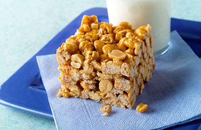 Chewy Caramel Bar sitting on a blue plate with a blue napkin and a glass of milk on the side.