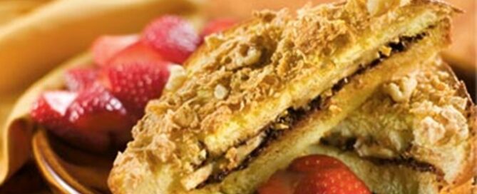 Honey Bunches of Oats Cinnamon Strawberry-Stuffed French Toast on a brown plate with sliced strawberries.