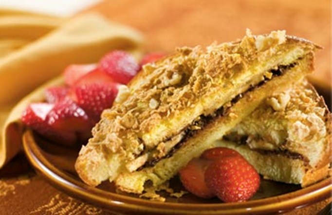 Honey Bunches of Oats Cinnamon Strawberry-Stuffed French Toast on a brown plate with sliced strawberries.