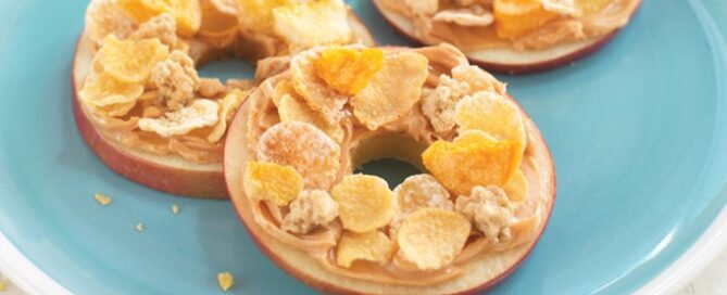 Three Crunchy Apple Rings with Honey Bunches of Oats on top sitting on a blue plate.