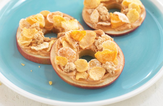 Three Crunchy Apple Rings with Honey Bunches of Oats on top sitting on a blue plate.