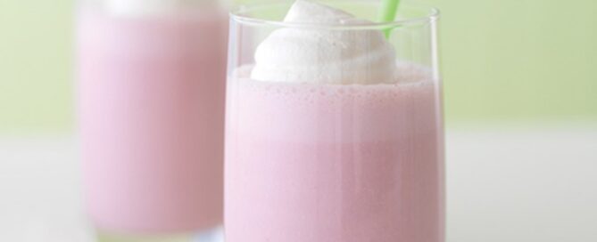Two glasses with double berry banana smoothie that is pink in color with a green straw.
