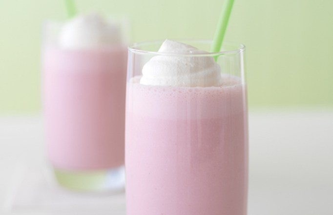 Two glasses with double berry banana smoothie that is pink in color with a green straw.