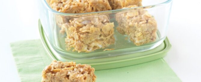 Trail mix cereal bars in a glass container on a green napkin.