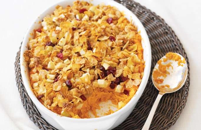 Cranberry Almond Crunch Mom’s Best Sweet Potato Casserole in a white bowl with a spoon on the side.