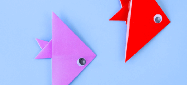 Purple and red origami paper fish on a blue background.