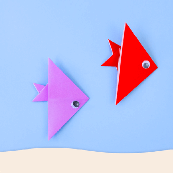 Purple and red origami paper fish on a blue background.