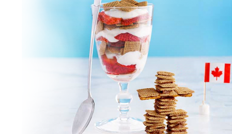 Shreddies All Canadian Breakfast Parfait in a clear glass on a blue background with a Canadian flag and a