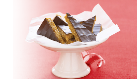 Honey Bunches of Oats Chocolate-Peanut Butter Bars cut into triangles sitting on a white platter on a red background.