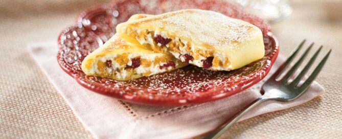 Cranberry Almond Crunch Blintzes on a red plate with a fork on the side.