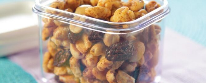 Sugar Crisp Sugar Bear Snack Mix in a clear container on a purple and blue tablecloth.