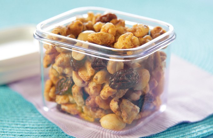 Sugar Crisp Sugar Bear Snack Mix in a clear container on a purple and blue tablecloth.