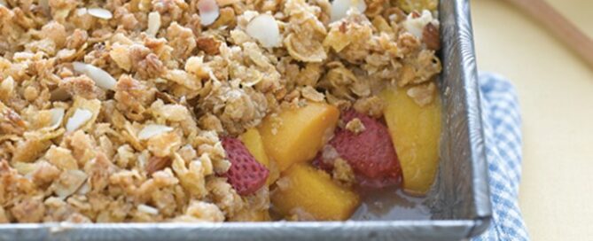 Strawberry Peach Crisp in a casserole pan on a white and blue checkered towel.
