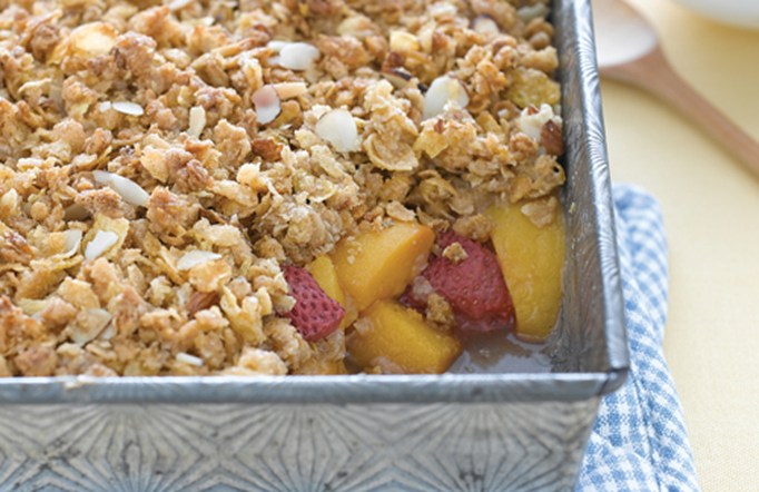Strawberry Peach Crisp in a casserole pan on a white and blue checkered towel.