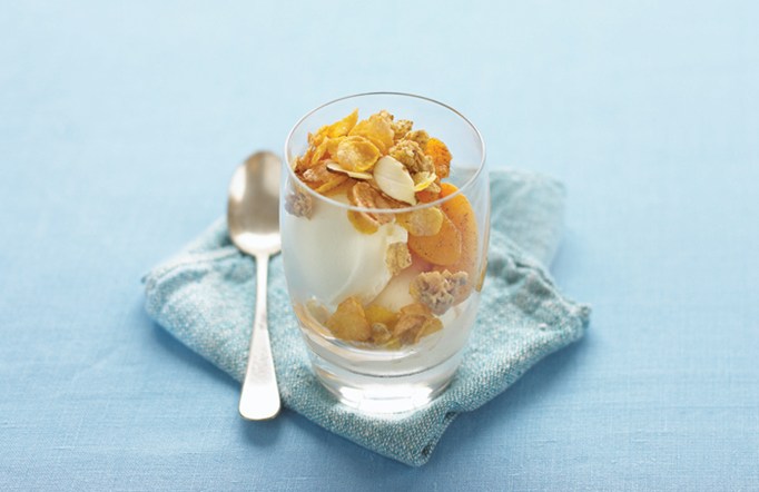Peach Crisp in a cup on a blue background and napkin with a spoon on the side.