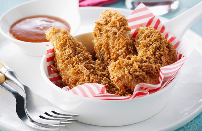 Shreddies Chicken Fingers in a white bowl with dipping sauce on the side.