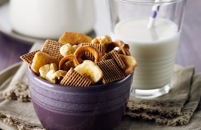 Shreddies Coco Crunch Mix in a purple bowl with a glass of milk in the background.