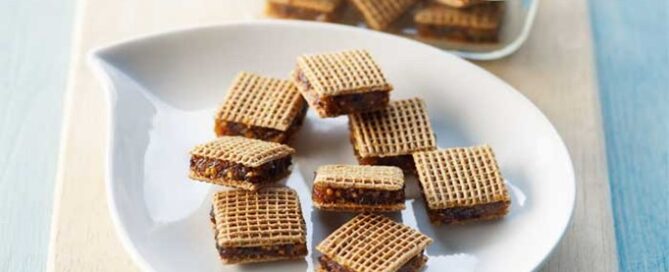 Shreddies “ON THE GO” Mini Fruit Snacks on a white plate with a wooden cutting board in the background.
