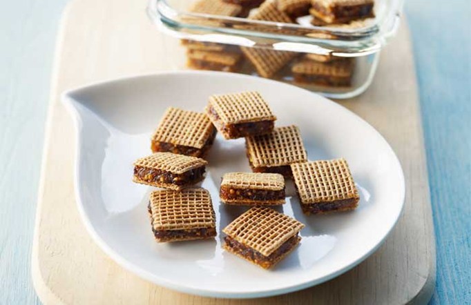 Shreddies “ON THE GO” Mini Fruit Snacks on a white plate with a wooden cutting board in the background.