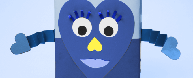 A blue paper heart with a face and arms, glued to a blue cereal box.